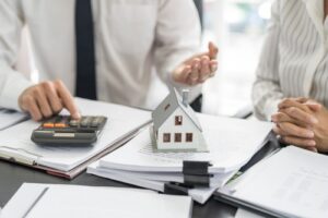 A man and woman sitting at a desk covered in paperwork discussing what is an apartment ledger.