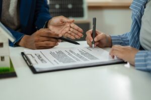 Close-up of two people discussing what is a guarantor on a lease and signing a contract.